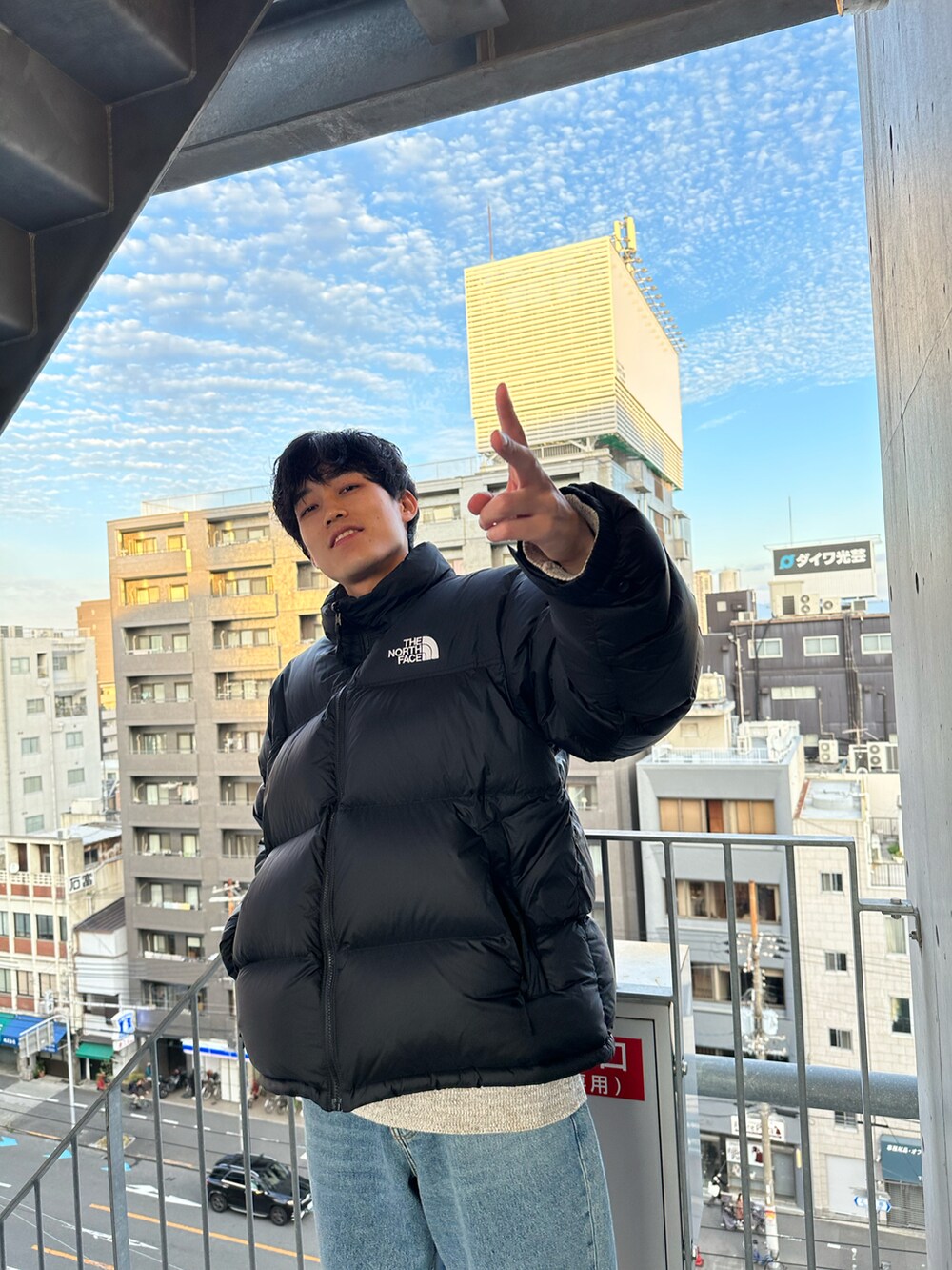 ブルー系のデニムパンツ、ベージュ系のスニーカー、ブラック系のダウンジャケット/コートを着用したメンズの秋コーディネートの2枚目の写真