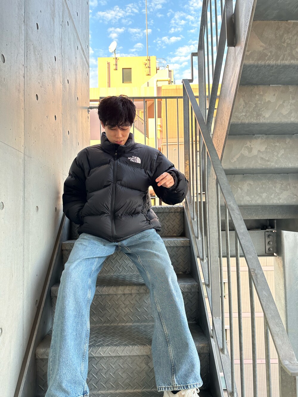 ブルー系のデニムパンツ、ベージュ系のスニーカー、ブラック系のダウンジャケット/コートを着用したメンズの秋コーディネートの3枚目の写真