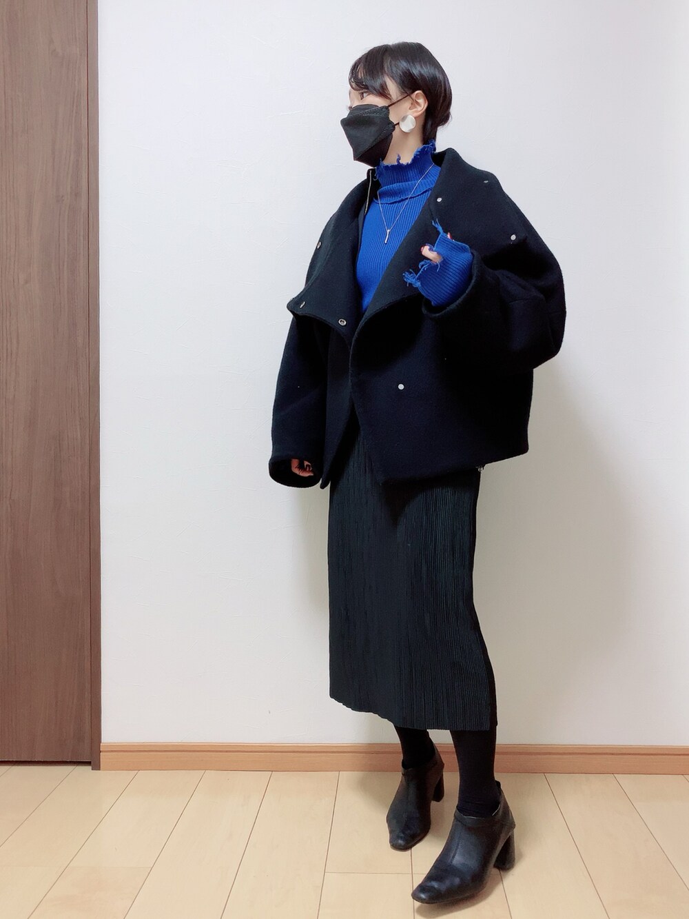 ブラック系のスカート、ブルー系のニット/セーター、ブラック系のその他アウターを着用したレディースの冬コーディネートの4枚目の写真