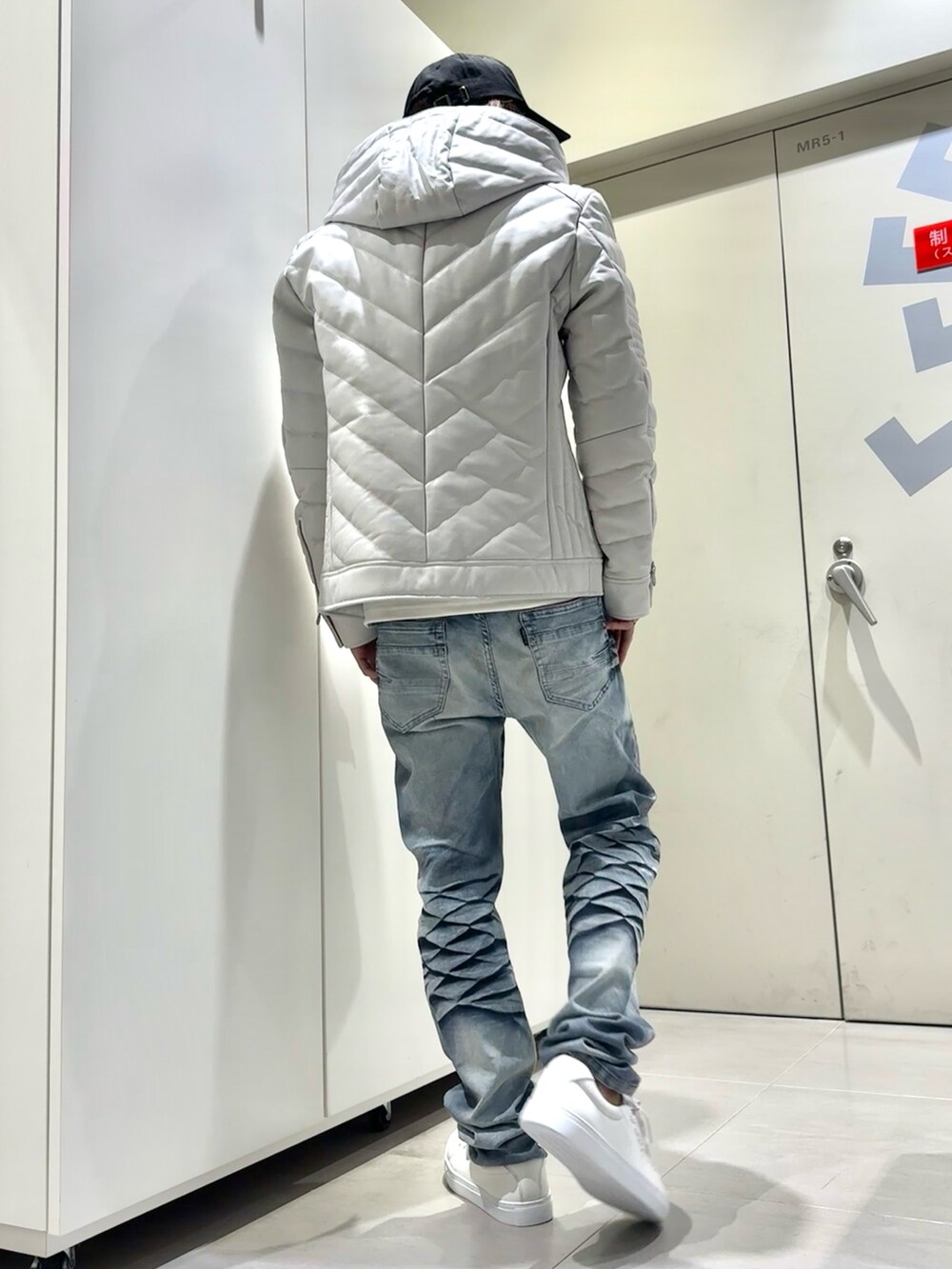 ブルー系のデニムパンツ、ホワイト系のTシャツ/カットソー、ホワイト系のダウンジャケット/コートを着用したメンズの秋コーディネートの3枚目の写真