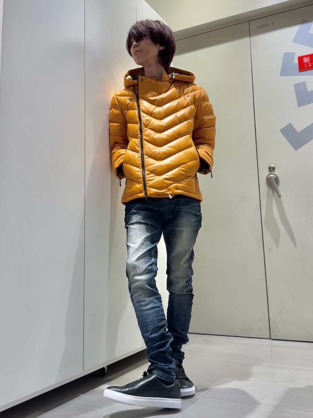 オレンジ系のダウンジャケット/コート、ブルー系のデニムパンツ、ブラック系のスニーカーを着用したメンズの秋コーディネートの5枚目の写真