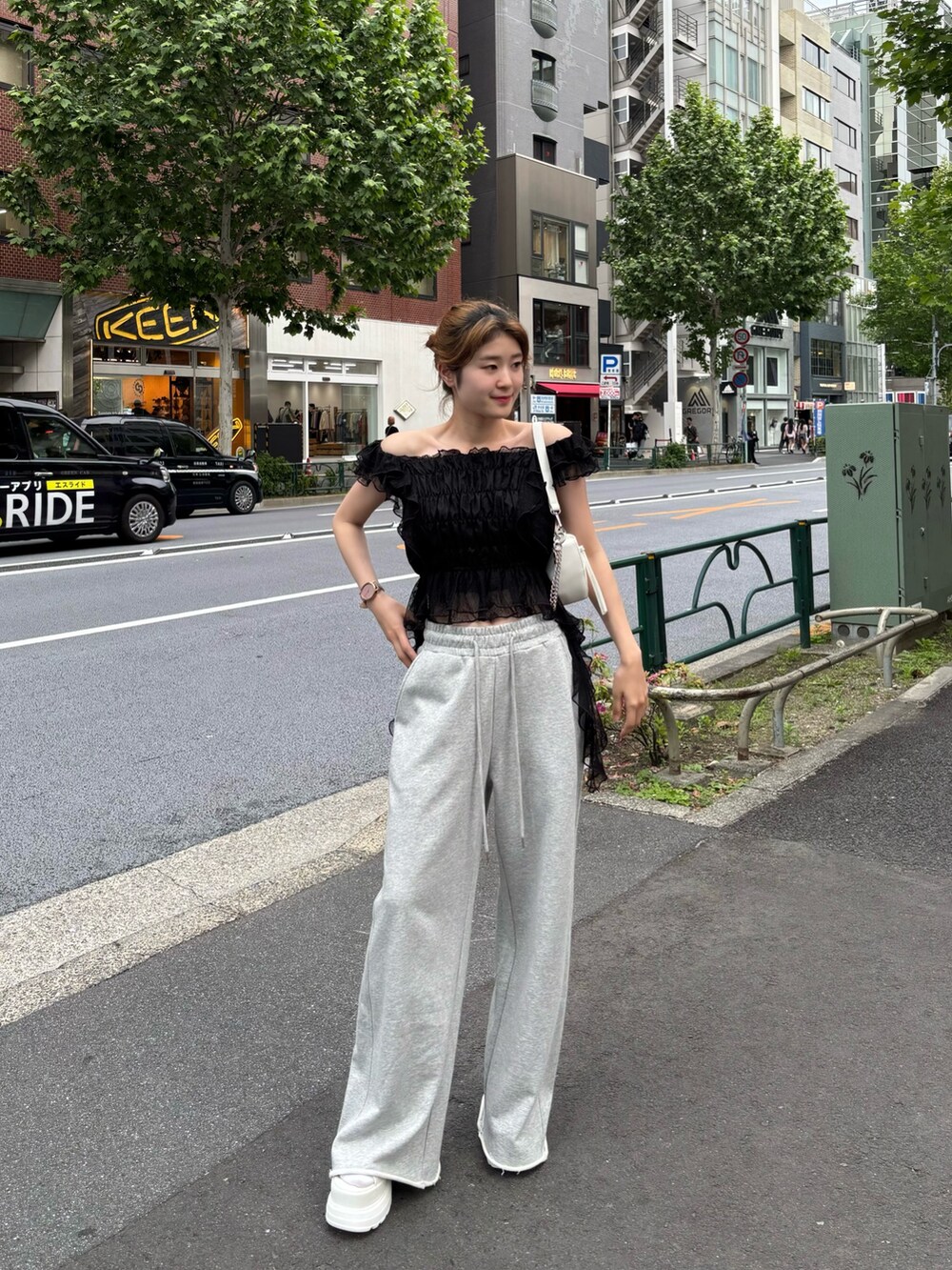 ブラック系のシャツ/ブラウス、グレー系のスウェットパンツ、ホワイト系のショルダーバッグを着用したレディースの春コーディネートの2枚目の写真