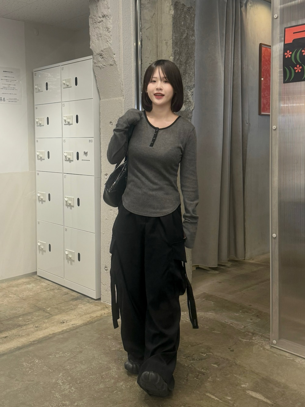 グレー系のTシャツ/カットソー、ブラック系のパンツ、ブラック系のスニーカーを着用したレディースの春コーディネートの2枚目の写真