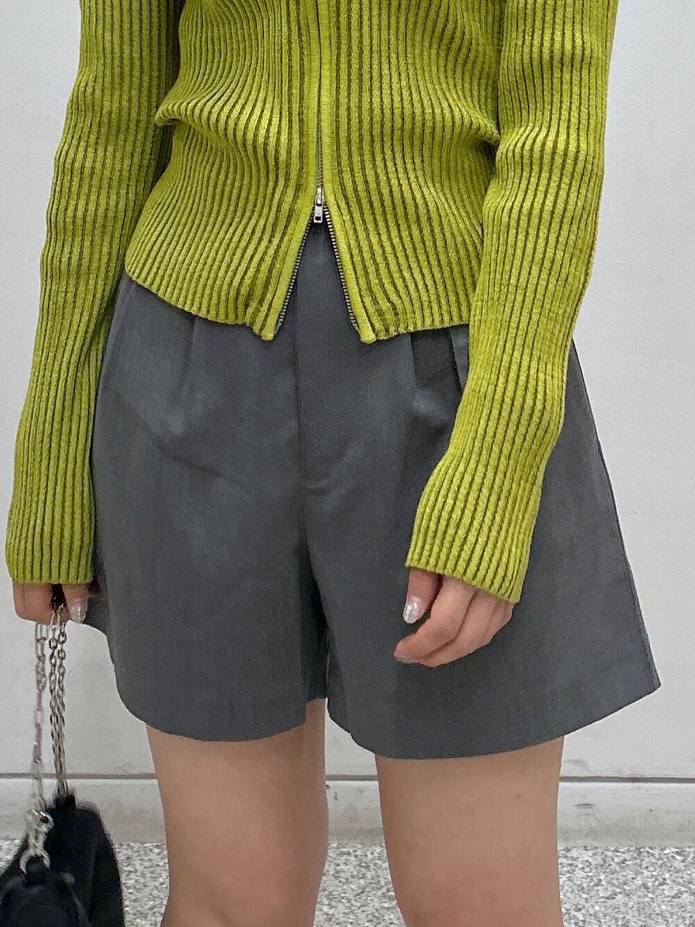 グレー系のその他パンツ、グリーン系のニット/セーター、ブラック系のハンドバッグを着用したレディースの秋コーディネートの3枚目の写真