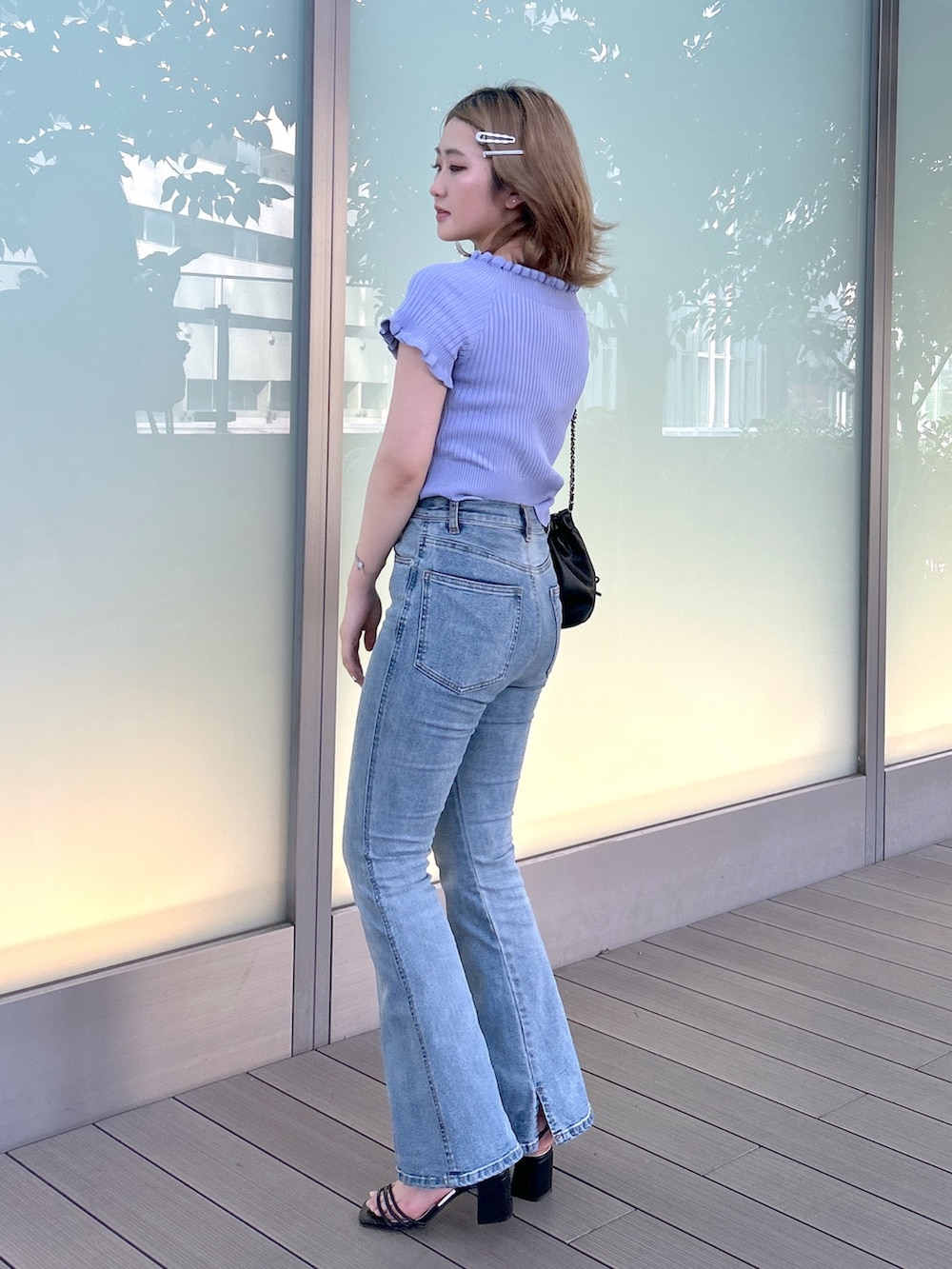 ブルー系のデニムパンツ、パープル系のニット/セーター、ブラック系のショルダーバッグを着用したレディースの夏コーディネートの2枚目の写真