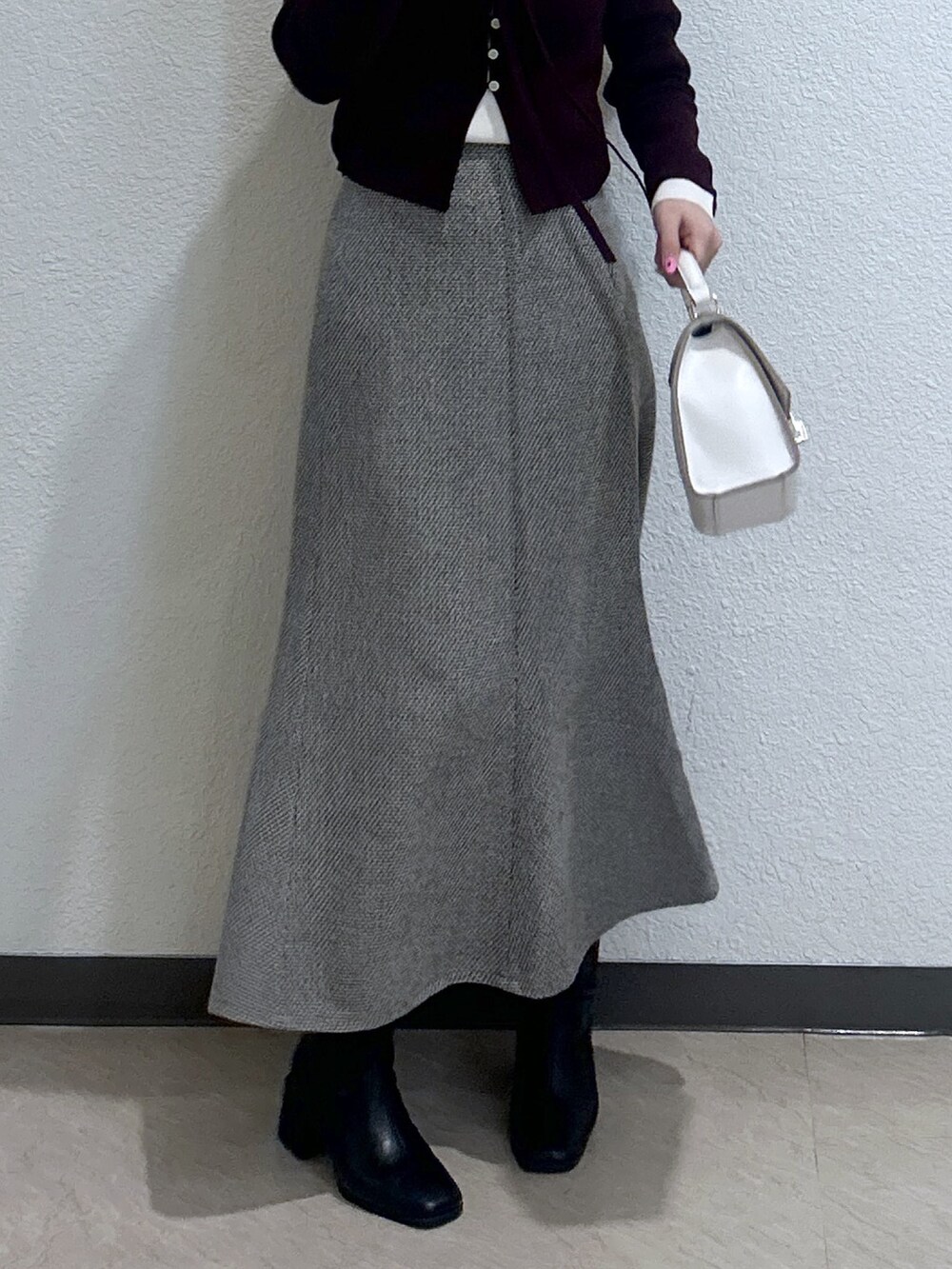 レッド系のニット/セーター、ホワイト系のトートバッグ、ブラック系のブーツを着用したレディースの冬コーディネートの3枚目の写真