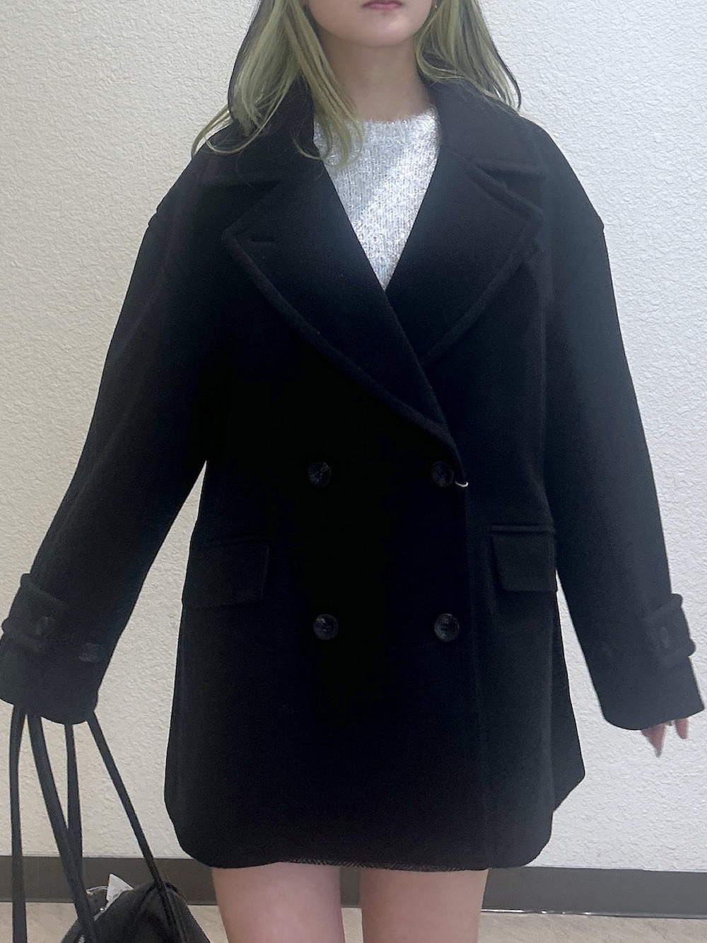 ブラウン系のピーコート、ホワイト系のニット/セーター、ブラック系のスカートを着用したレディースの冬コーディネートの2枚目の写真