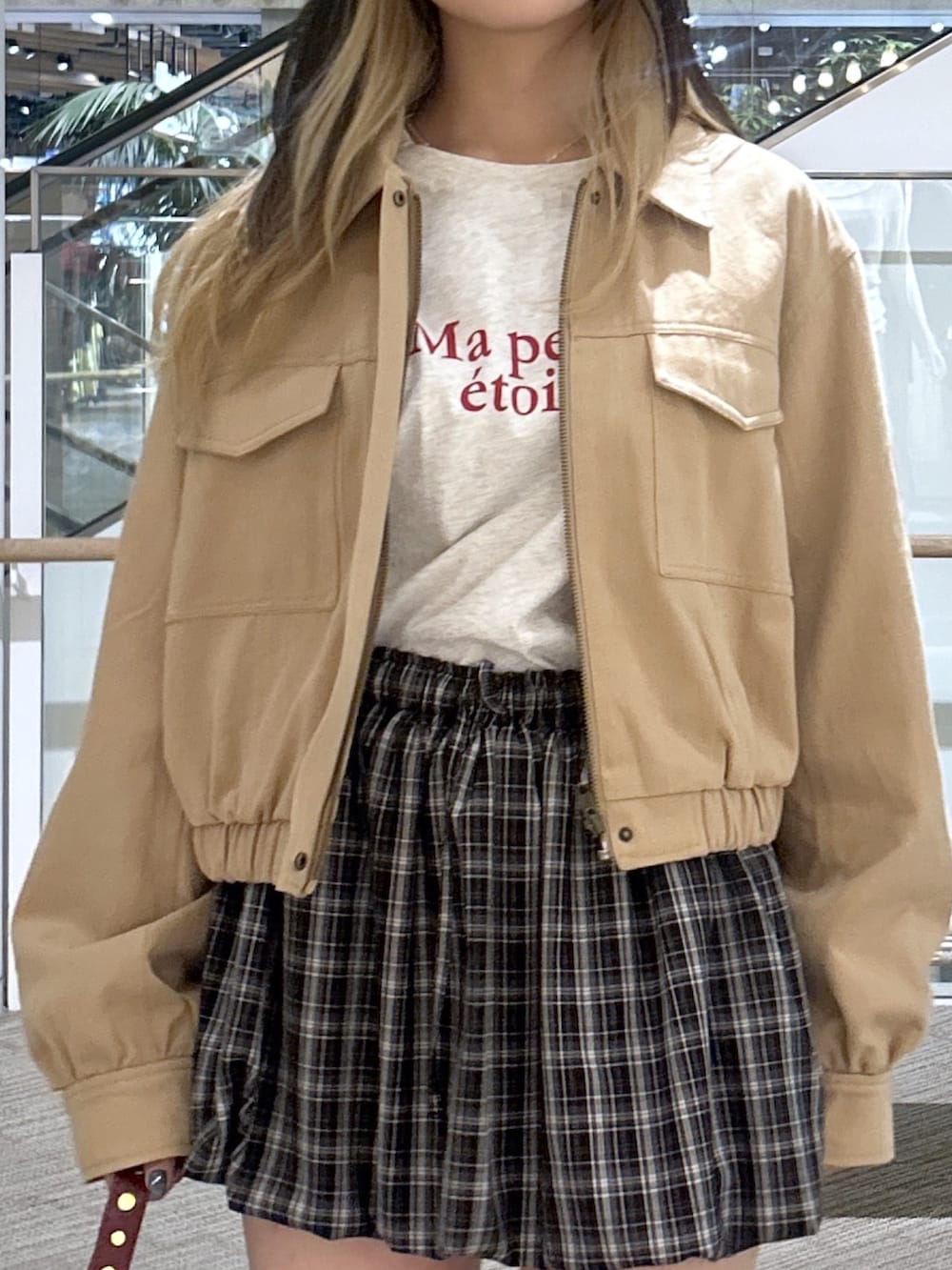 ベージュ系のブルゾン、ホワイト系のTシャツ/カットソー、ブラック系のスカートを着用したレディースの春コーディネートの2枚目の写真