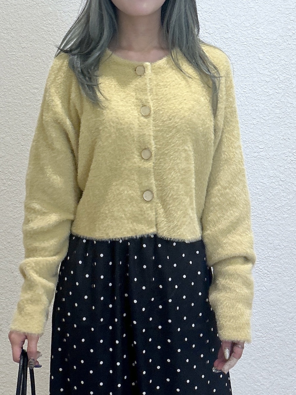 ブラック系のスカート、イエロー系のニット/セーター、ブラック系のショルダーバッグを着用したレディースの秋コーディネートの2枚目の写真