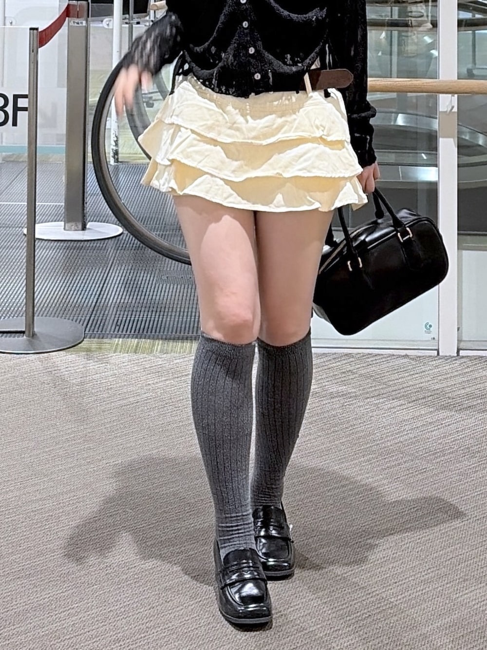 ホワイト系のスカート、ブラック系のTシャツ/カットソー、ブラウン系のローファーを着用したレディースの春コーディネートの3枚目の写真