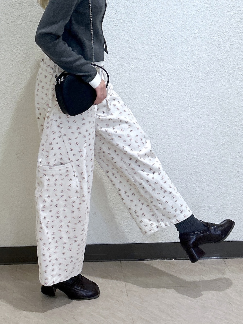 レッド系のニット/セーター、ホワイト系のデニムパンツ、ブラック系のショルダーバッグを着用したレディースの冬コーディネートの3枚目の写真