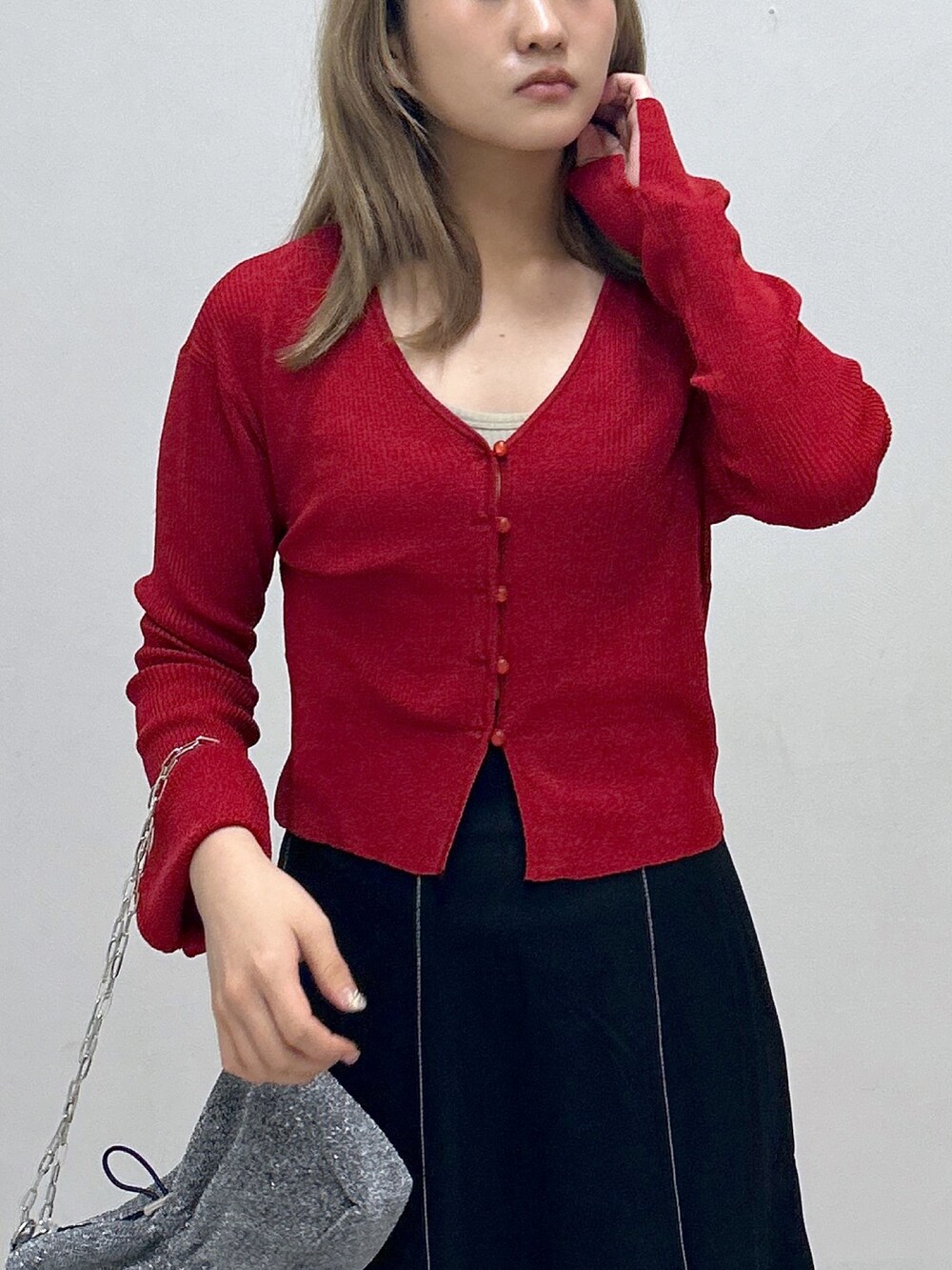 ブラック系のスカート、レッド系のニット/セーター、ブラック系のハンドバッグを着用したレディースの秋コーディネートの2枚目の写真