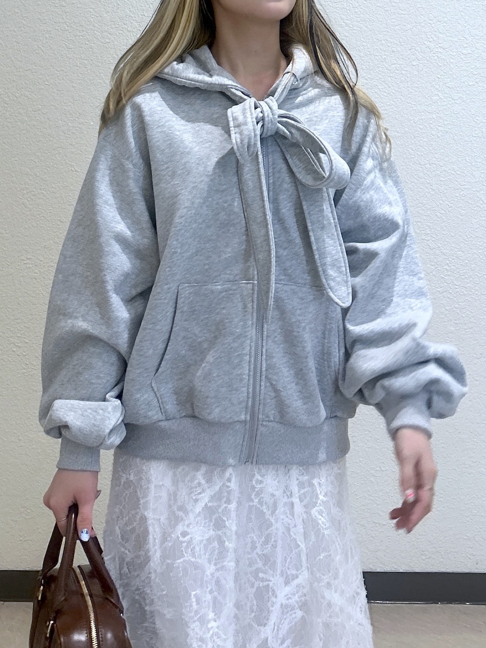 グレー系のパーカー、ホワイト系のスカート、ブラウン系のローファーを着用したレディースの冬コーディネートの2枚目の写真