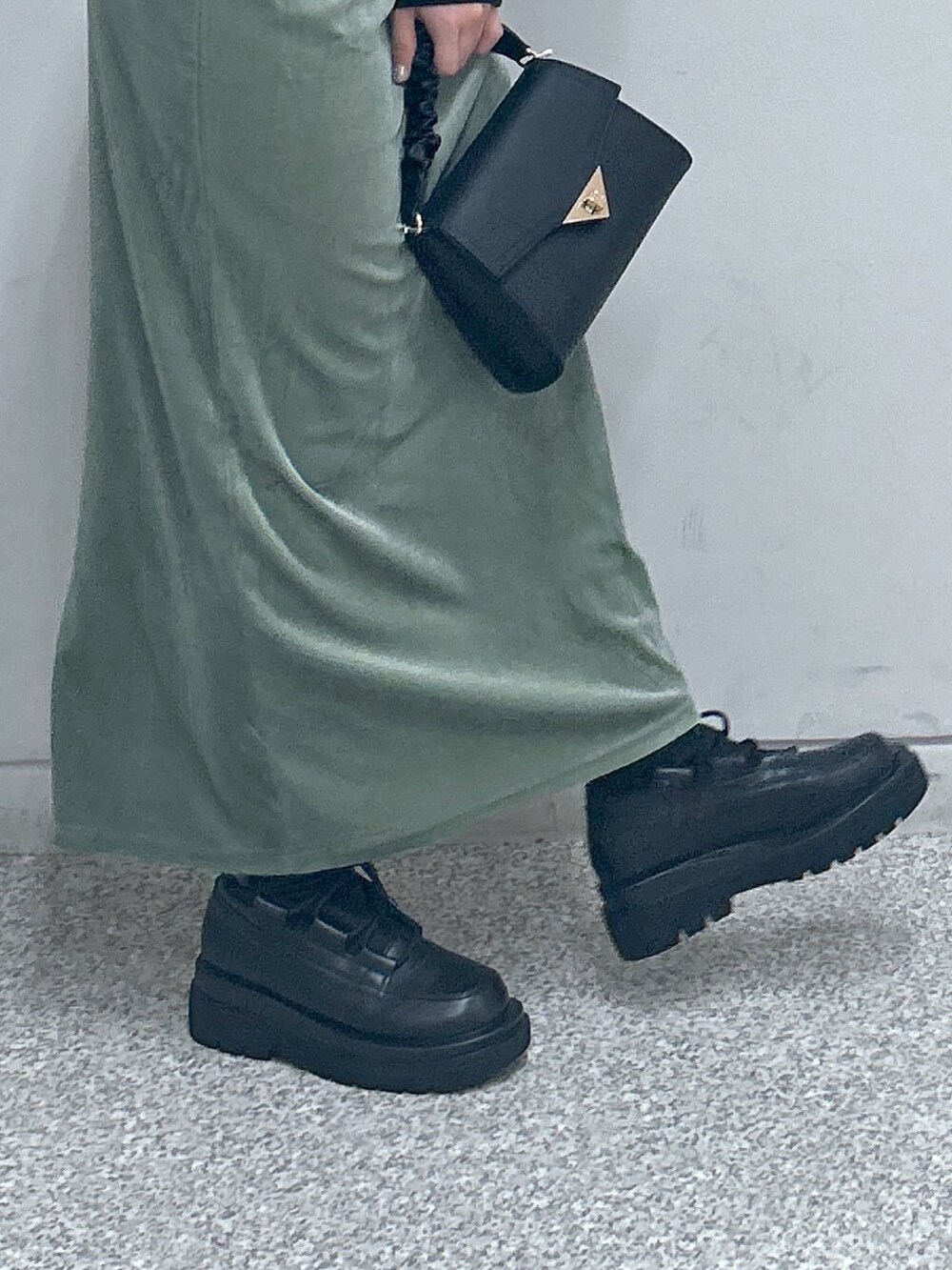 グリーン系のワンピース、ブラック系のニット/セーター、ブラック系のショルダーバッグを着用したレディースの秋コーディネートの3枚目の写真