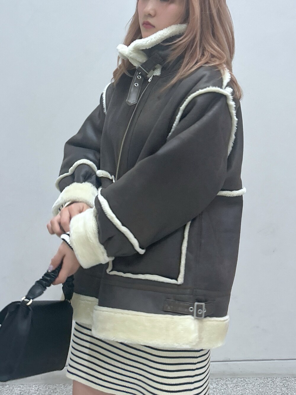 ブラウン系のブルゾン、ホワイト系のワンピース、ブラック系のショルダーバッグを着用したレディースの秋コーディネートの2枚目の写真