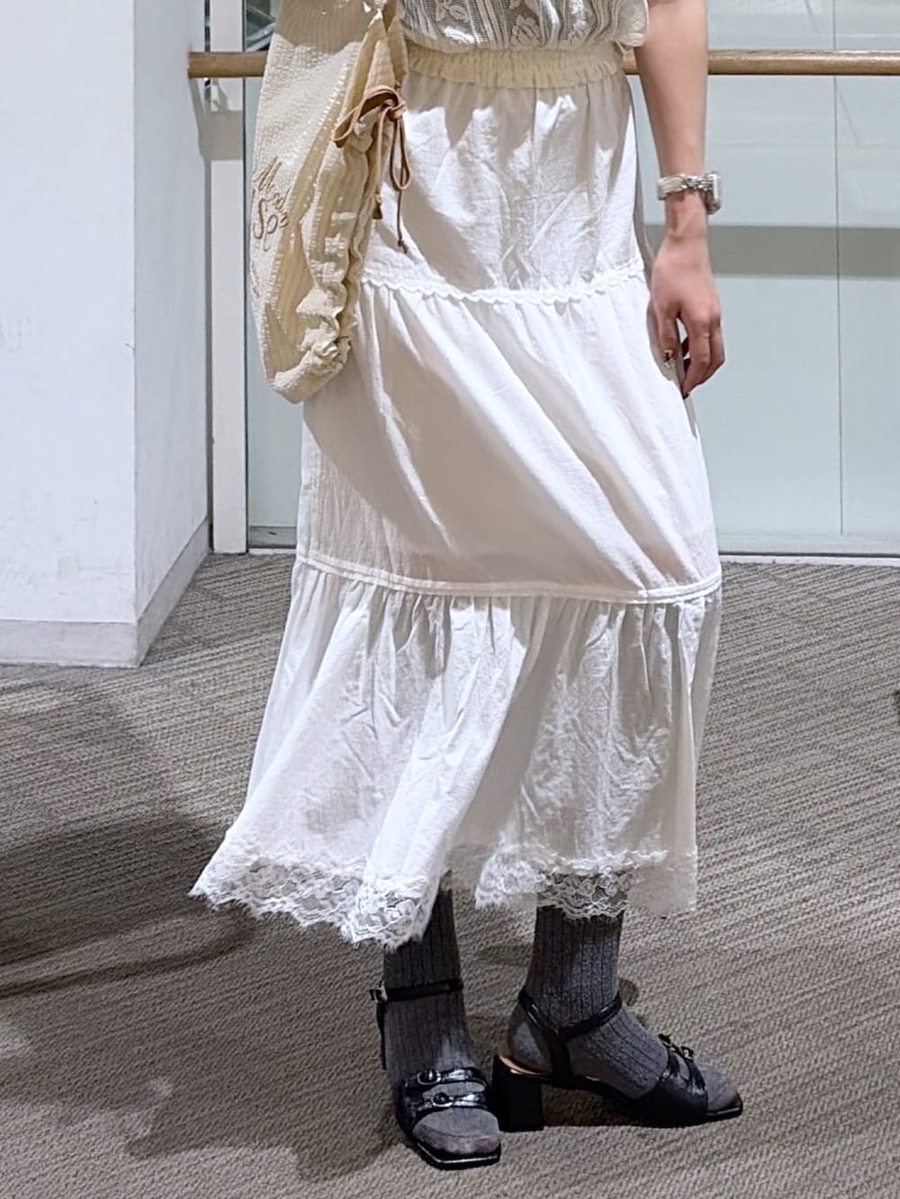 ホワイト系のシャツ/ブラウス、ホワイト系のスカート、ブルー系のトートバッグを着用したレディースの夏コーディネートの3枚目の写真