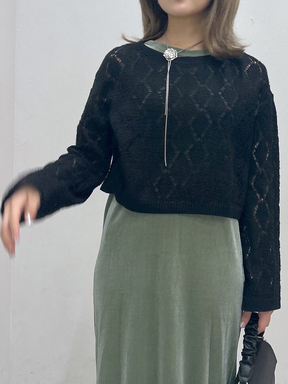 グリーン系のワンピース、ブラック系のニット/セーター、ブラック系のショルダーバッグを着用したレディースの秋コーディネートの2枚目の写真