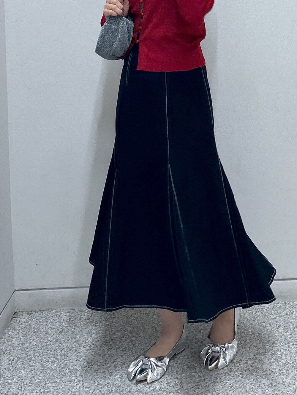 ブラック系のスカート、レッド系のニット/セーター、ブラック系のハンドバッグを着用したレディースの秋コーディネートの3枚目の写真