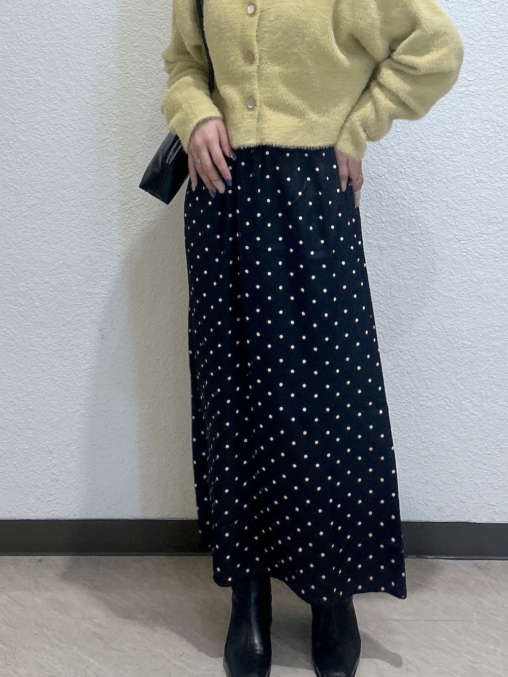 ブラック系のスカート、イエロー系のニット/セーター、ブラック系のショルダーバッグを着用したレディースの秋コーディネートの3枚目の写真