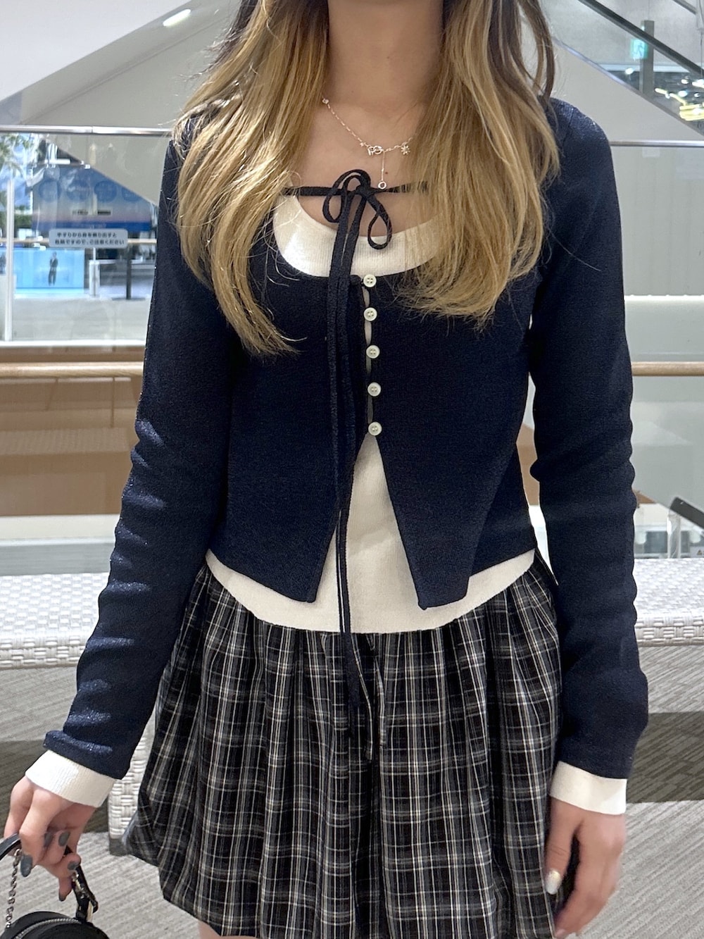 ブルー系のニット/セーター、ブラウン系のブーツ、ブラック系のスカートを着用したレディースの春コーディネートの2枚目の写真