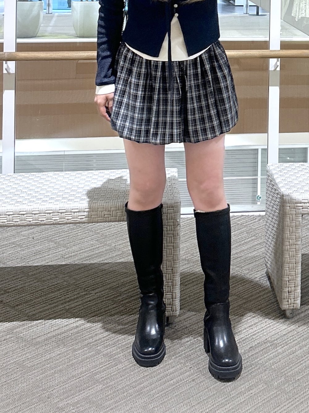 ブルー系のニット/セーター、ブラウン系のブーツ、ブラック系のスカートを着用したレディースの春コーディネートの3枚目の写真