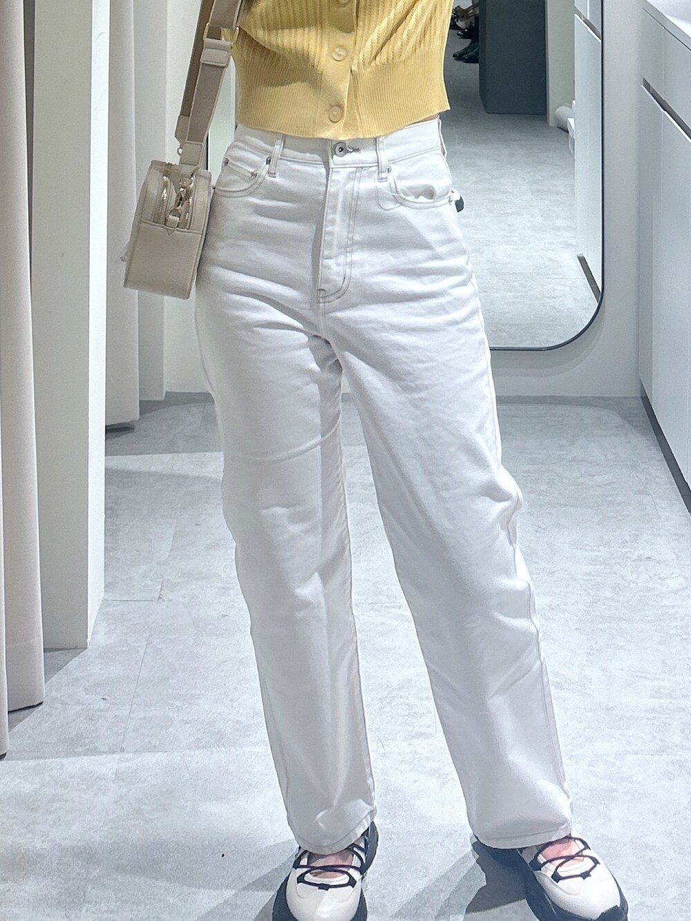 ブラック系のデニムパンツ、イエロー系のTシャツ/カットソー、ホワイト系のショルダーバッグを着用したレディースの春コーディネートの3枚目の写真