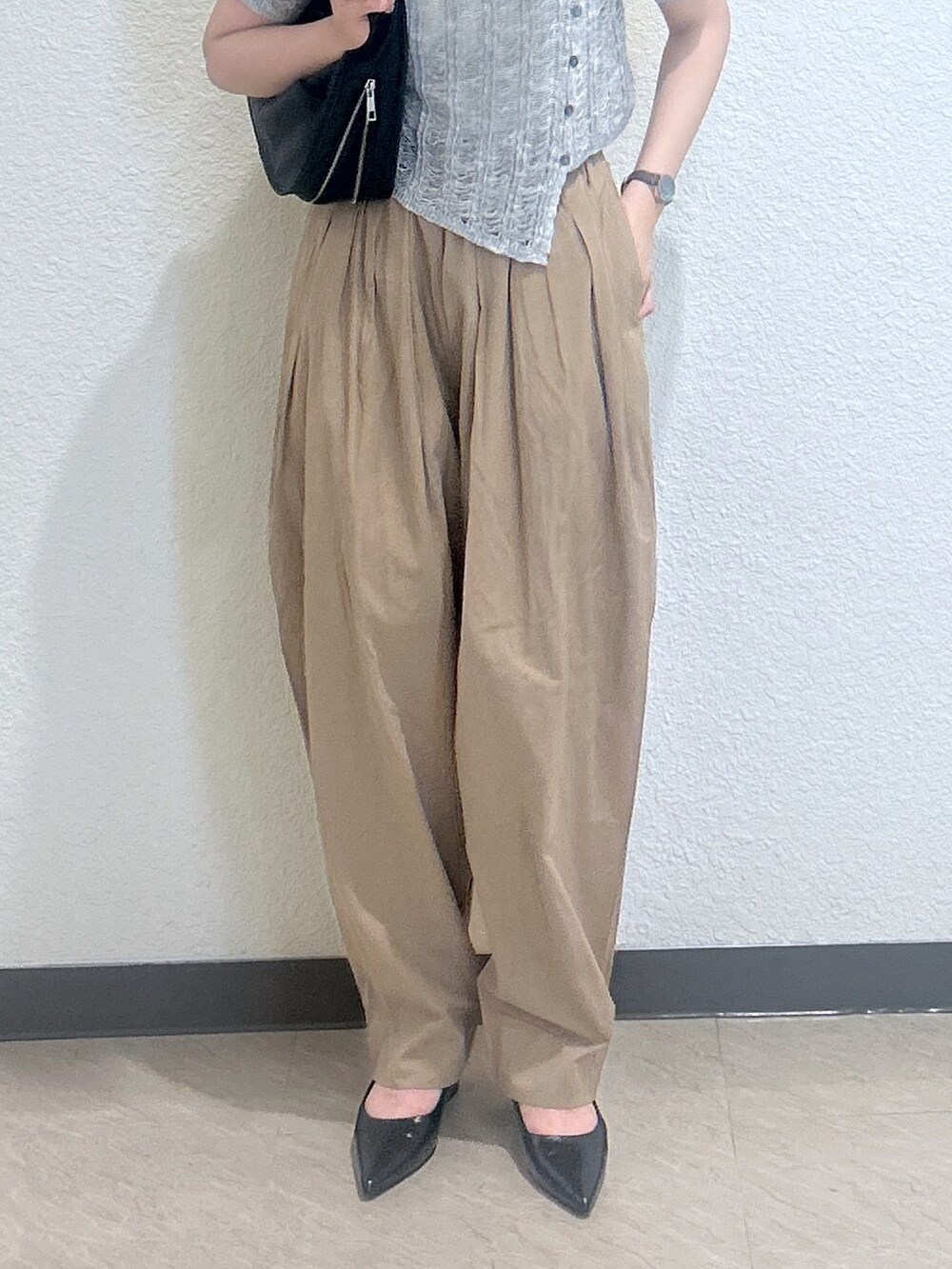 ブラック系のハンドバッグ、グレー系のニット/セーター、ブラウン系のパンプスを着用したレディースの夏コーディネートの3枚目の写真