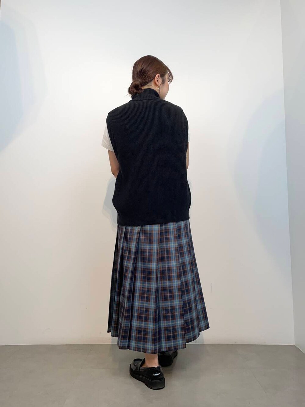 ホワイト系のTシャツ/カットソー、ブラック系のベスト、ブラウン系のハンドバッグを着用したレディースの秋コーディネートの2枚目の写真