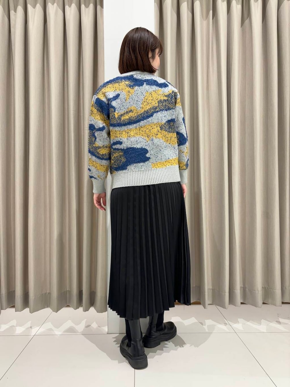 グレー系のニット/セーター、ブラック系のスカートを着用したレディースの秋コーディネートの2枚目の写真