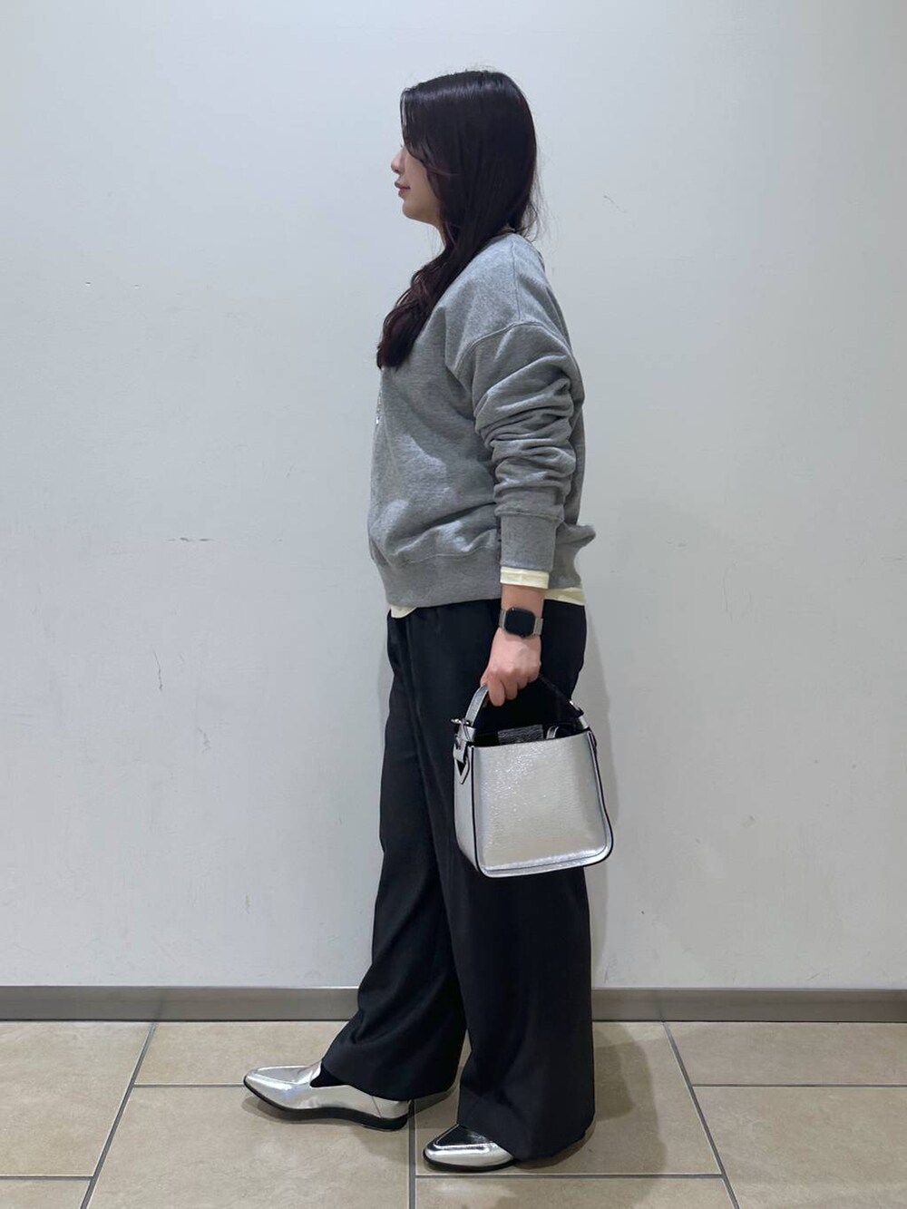 シルバー系のローファー、ベージュ系のTシャツ/カットソー、シルバー系のショルダーバッグを着用したレディースの冬コーディネートの2枚目の写真