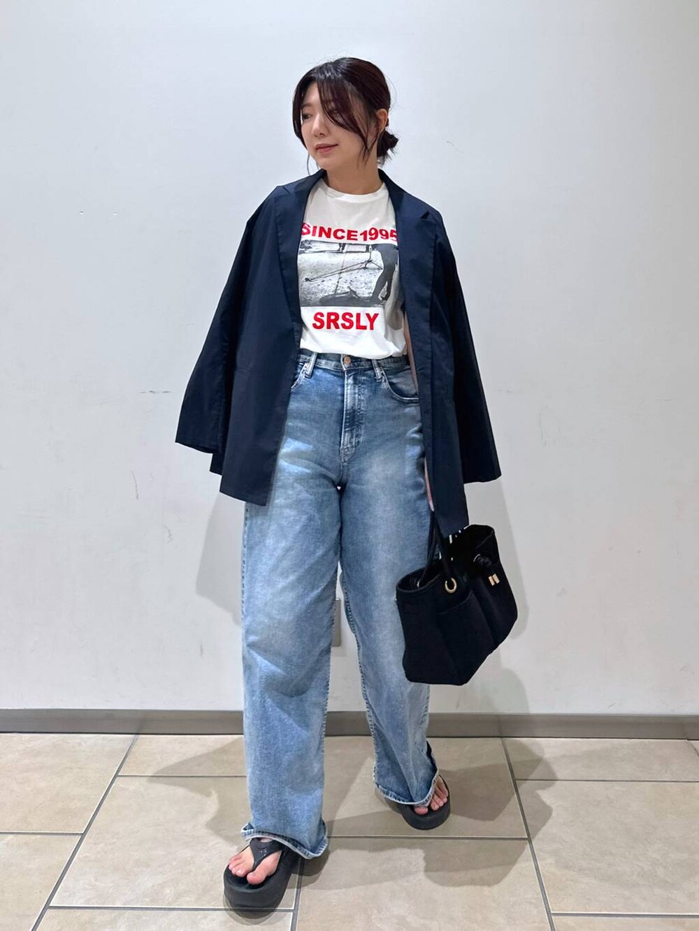 ブラック系のトートバッグ、ブルー系のデニムパンツ、ホワイト系のTシャツ/カットソーを着用したレディースの夏コーディネートの4枚目の写真