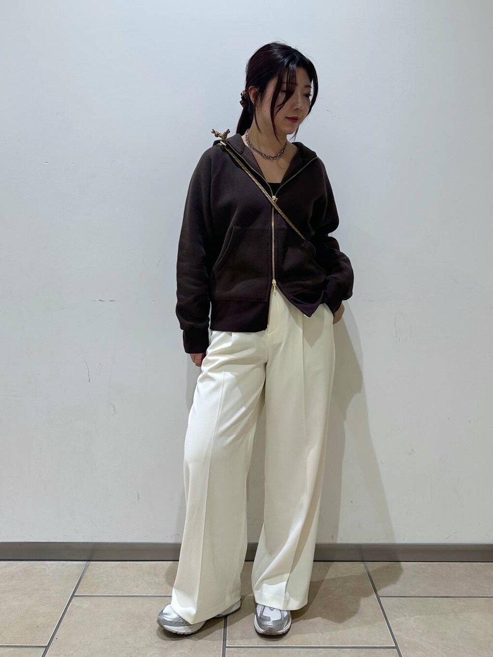 ブラウン系のパーカー、ベージュ系のショルダーバッグ、ホワイト系のスラックスを着用したレディースの冬コーディネートの4枚目の写真