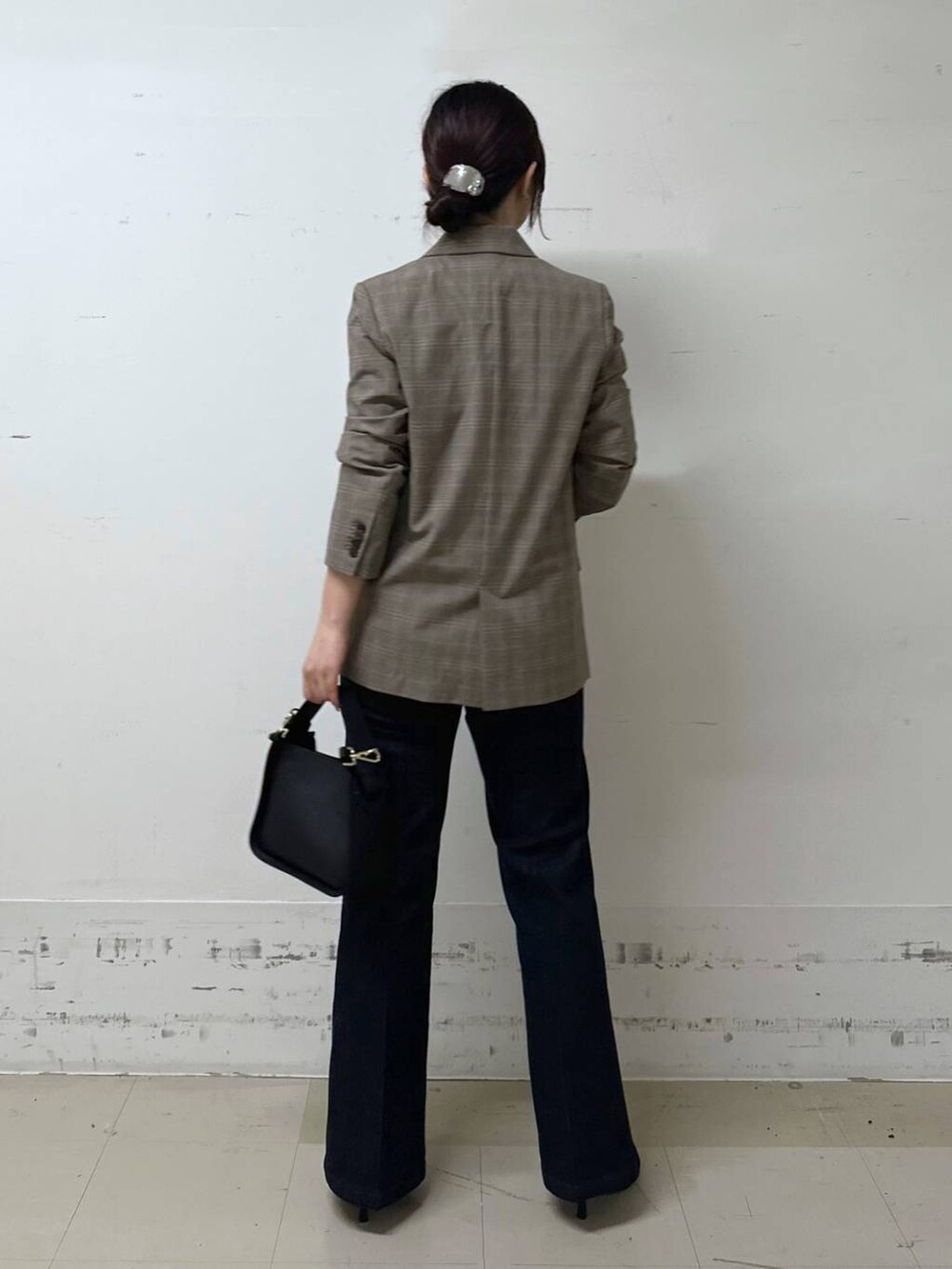 ブラック系のハンドバッグ、ブラック系のキャミソール、ブルー系のデニムパンツを着用したレディースの夏コーディネートの3枚目の写真