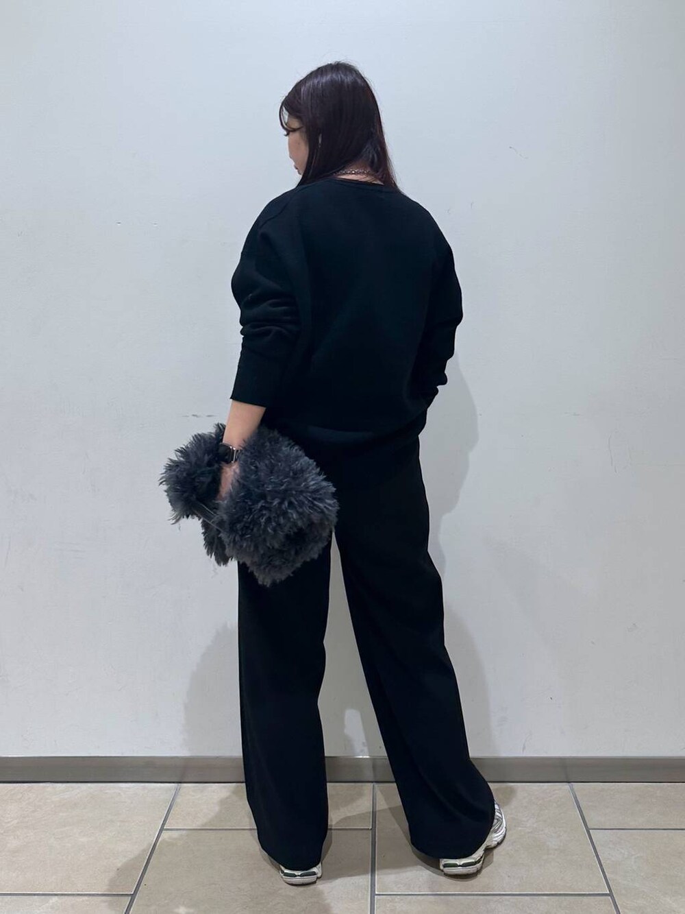 グレー系のトートバッグ、ブラック系のスラックス、ブラック系のニット/セーターを着用したレディースの冬コーディネートの3枚目の写真