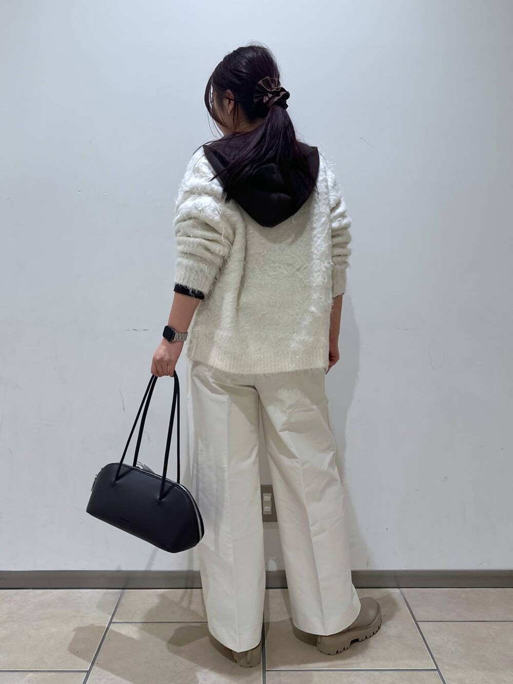 ブラック系のトートバッグ、ホワイト系のカーディガン/ボレロ、ベージュ系のブーツを着用したレディースの冬コーディネートの3枚目の写真