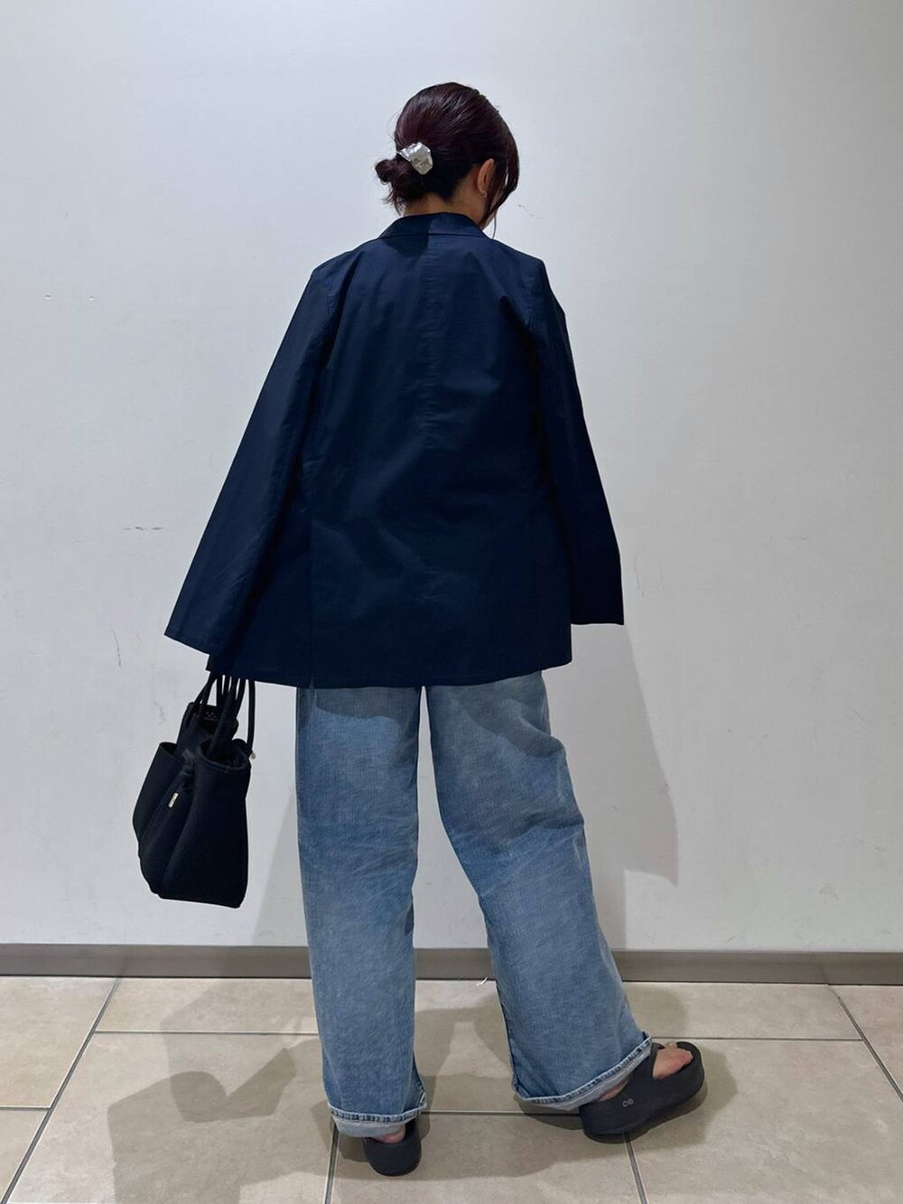 ブラック系のトートバッグ、ブルー系のデニムパンツ、ホワイト系のTシャツ/カットソーを着用したレディースの夏コーディネートの3枚目の写真