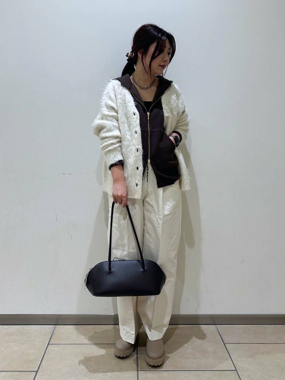 ブラック系のトートバッグ、ホワイト系のカーディガン/ボレロ、ベージュ系のブーツを着用したレディースの冬コーディネートの4枚目の写真