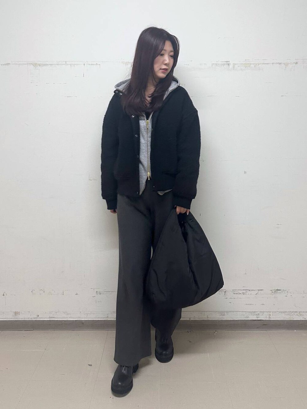 ブラック系のブルゾン、グレー系のパーカー、ブラック系のブーツを着用したレディースの秋コーディネートの4枚目の写真