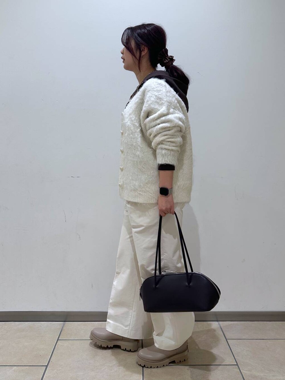 ブラック系のトートバッグ、ホワイト系のカーディガン/ボレロ、ベージュ系のブーツを着用したレディースの冬コーディネートの2枚目の写真