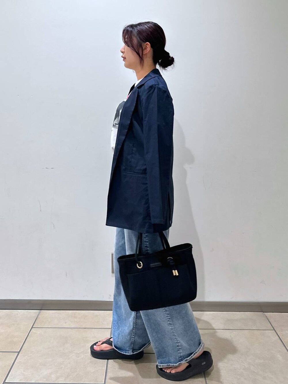 ブラック系のトートバッグ、ブルー系のデニムパンツ、ホワイト系のTシャツ/カットソーを着用したレディースの夏コーディネートの2枚目の写真