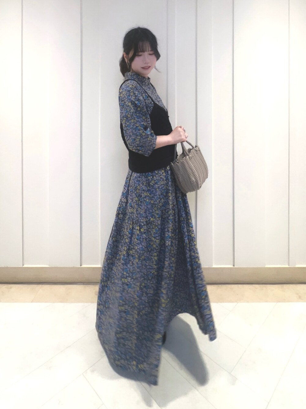 グレー系のかごバッグ、グレー系のワンピース、ブラック系のパンプスを着用したレディースの夏コーディネートの2枚目の写真