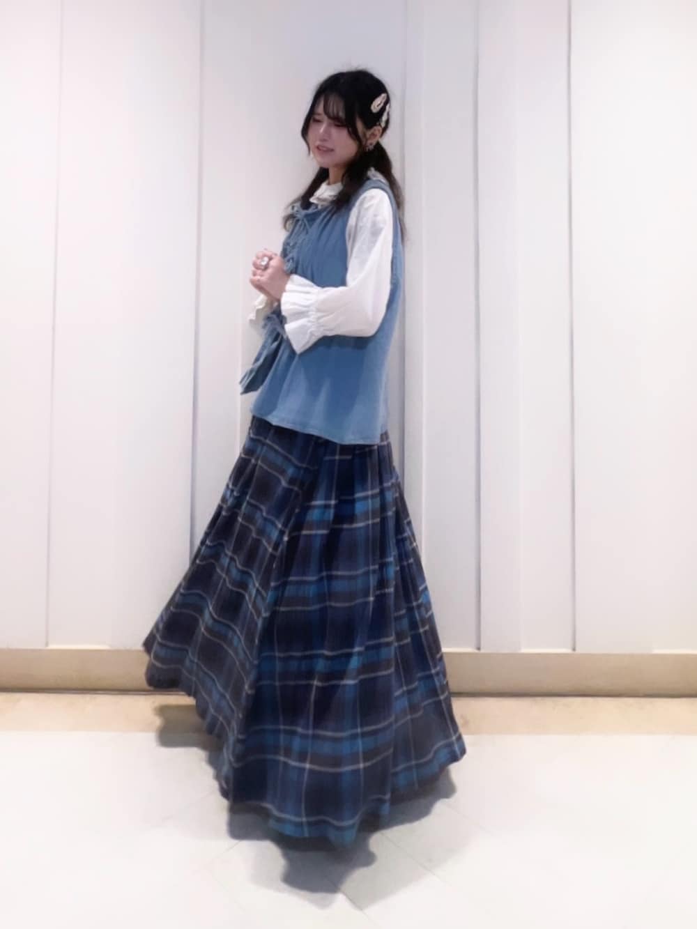 ブルー系のベスト、ブルー系のスカート、ブラック系のその他シューズを着用したレディースの春コーディネートの2枚目の写真