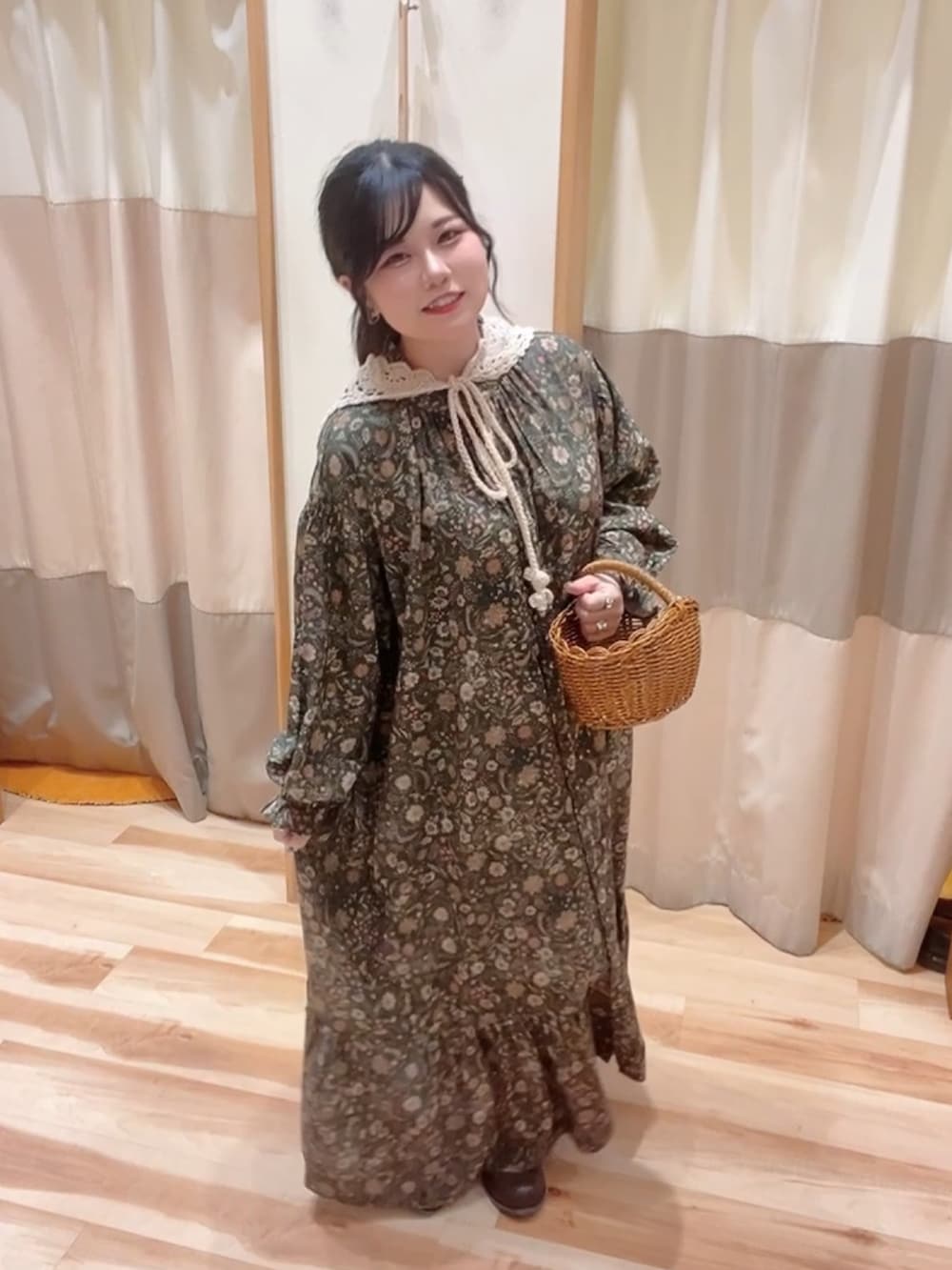 グリーン系のワンピース、ブラウン系のドレスシューズ、ブラウン系のかごバッグを着用したレディースの秋コーディネートの2枚目の写真