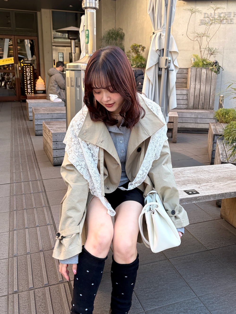 ベージュ系のトレンチコート、グレー系のTシャツ/カットソー、ブラック系のソックス/靴下を着用したレディースの冬コーディネートの4枚目の写真