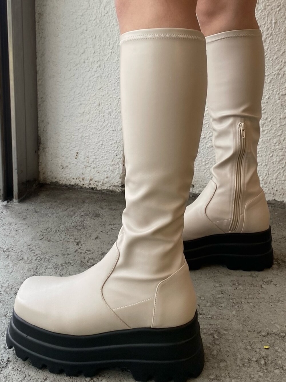 グレー系のテーラードジャケット、ブラック系のデニムスカート、ブラック系のブーツを着用したレディースの冬コーディネートの5枚目の写真