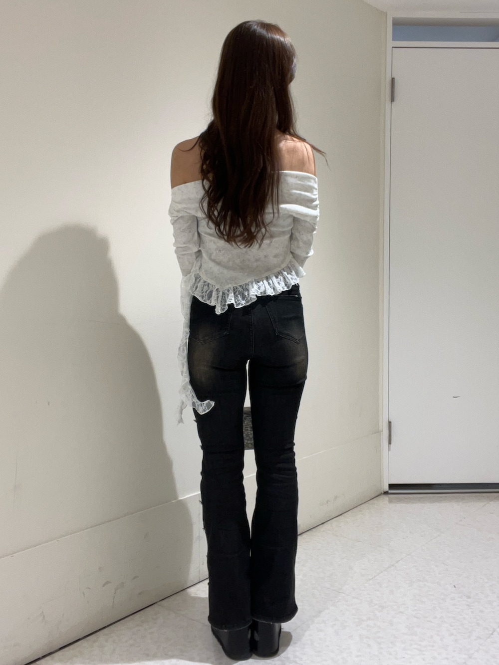 シルバー系のショルダーバッグ、ホワイト系のTシャツ/カットソー、ブラック系のデニムパンツを着用したレディースの冬コーディネートの3枚目の写真