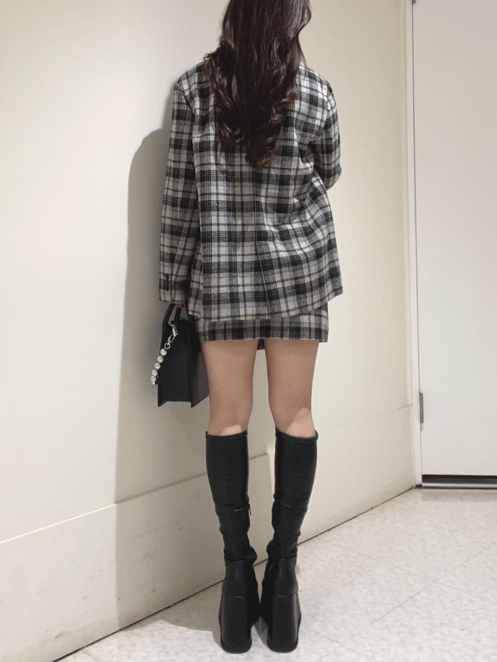 グレー系のテーラードジャケット、グレー系のスカート、ブラック系のブーツを着用したレディースの秋コーディネートの3枚目の写真