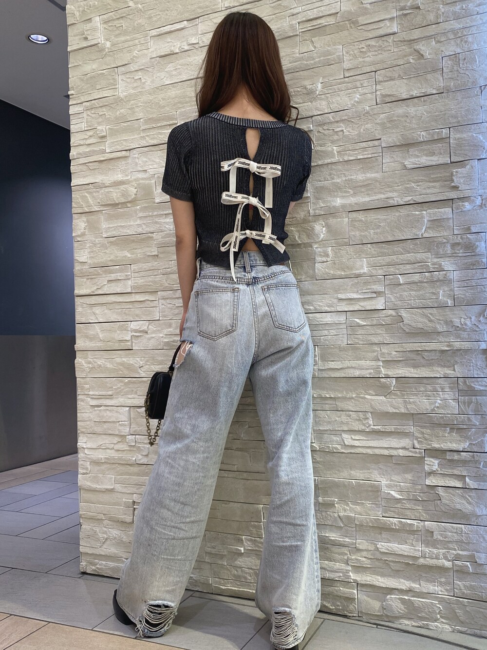 ブラック系のニット/セーター、ブルー系のデニムパンツ、その他のショルダーバッグを着用したレディースの夏コーディネートの3枚目の写真