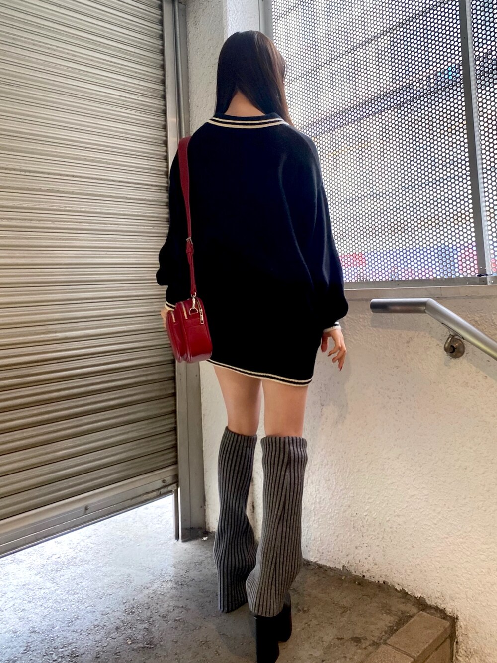 ブラック系のニット/セーター、レッド系のショルダーバッグ、グレー系のレッグウォーマーを着用したレディースの冬コーディネートの3枚目の写真