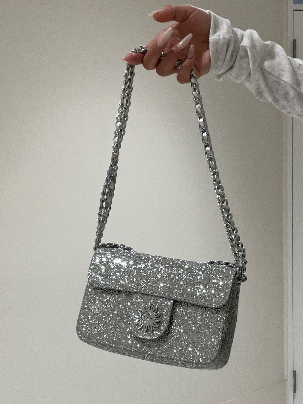 シルバー系のショルダーバッグ、ホワイト系のTシャツ/カットソー、ブラック系のデニムパンツを着用したレディースの冬コーディネートの6枚目の写真